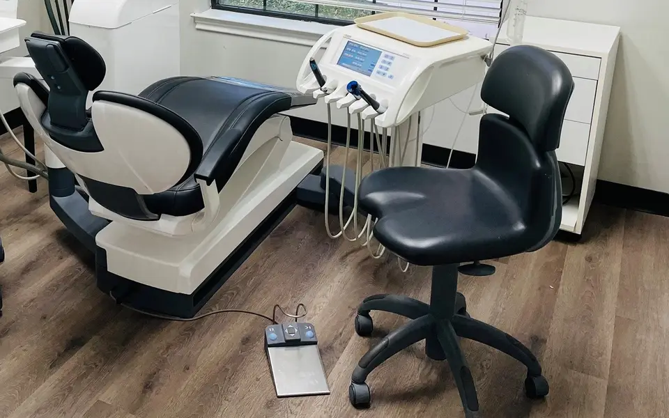 A dental chair and a stool in one of our treatment rooms, with the instrument tray beside them