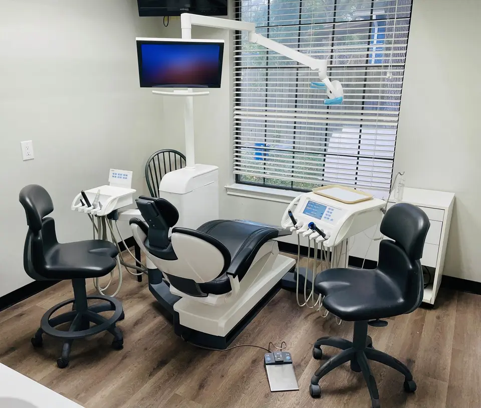 One of our treatment rooms: a dental chair, two stools, the instrument trays and a window with blinds